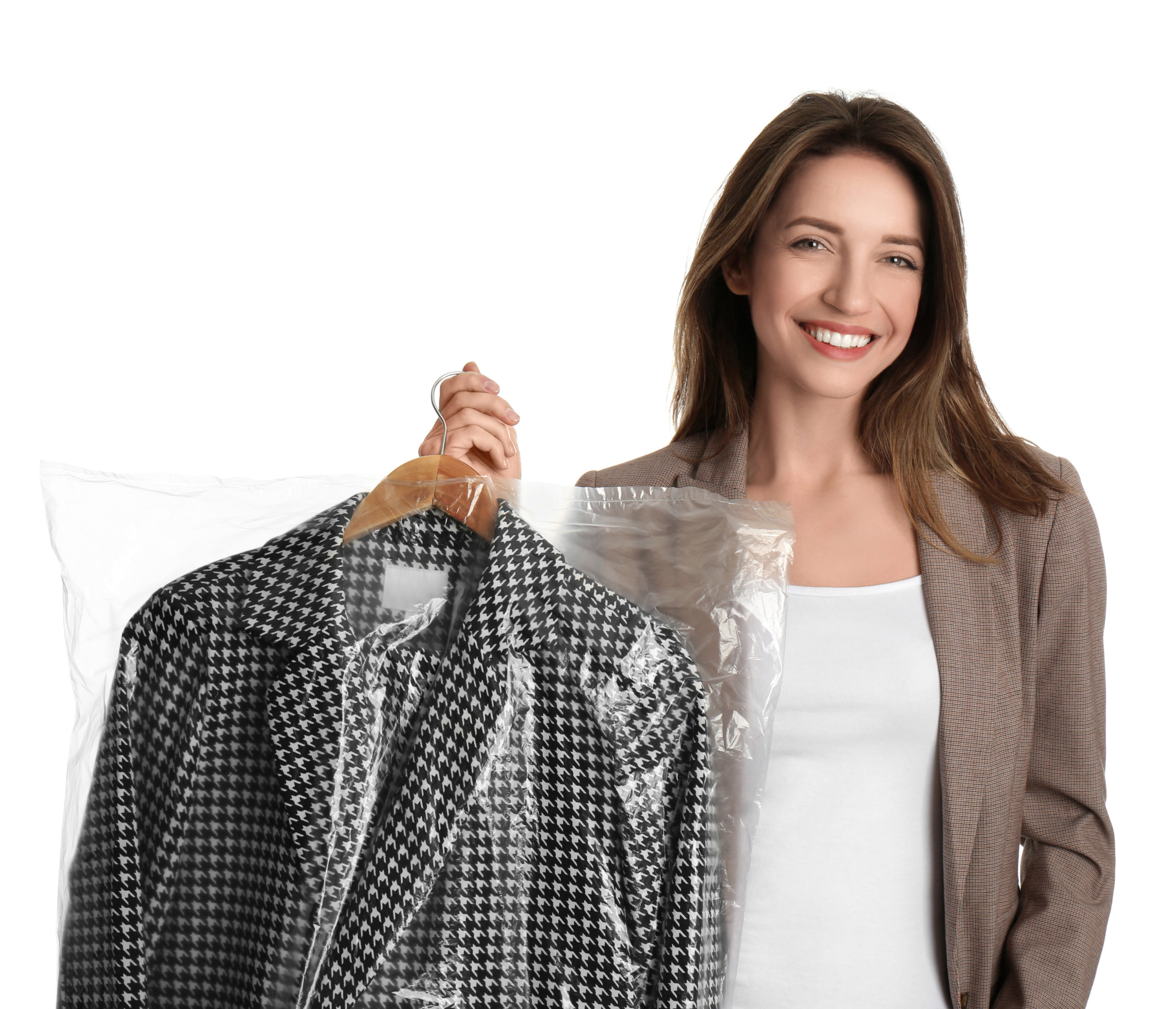 Young woman holding hanger with jacket in plastic bag on white b